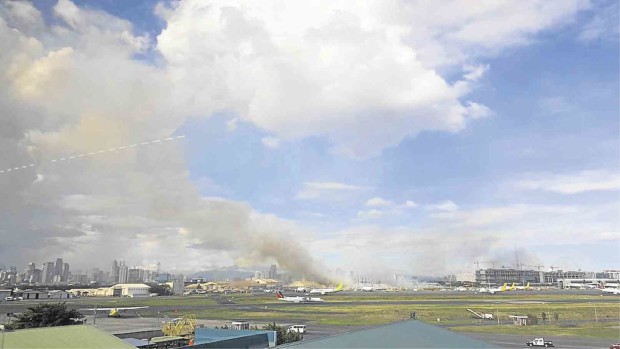 SMOKE rises from a burning patch of grass near Naia Terminal 3 on Thursday. KAT ESTOR/CONTRIBUTOR
