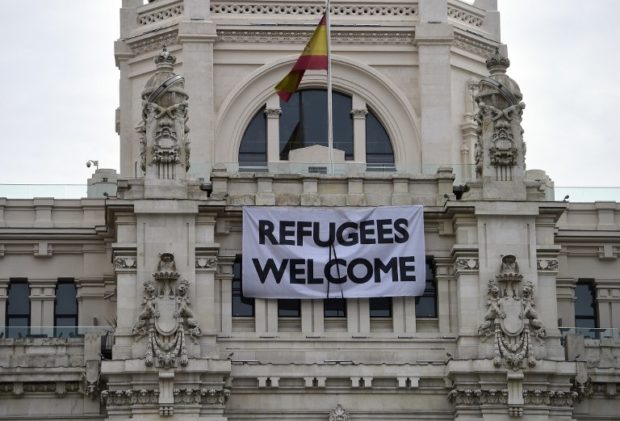 A banner with a black ribbon on it and reading "Refugees Welcome" hangs on the facade of Madrid's town hall on March 18, 2016. AFP FILE PHOTO