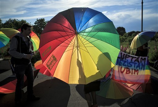A girl casts a shadow on a rainbow colored umbrella next to a banner that reads: "We Fight, We Resist, We Love", as people celebrate the International Day Against Homophobia in Bucharest, Romania, Tuesday, May 17, 2016. (AP Photo/Vadim Ghirda) 