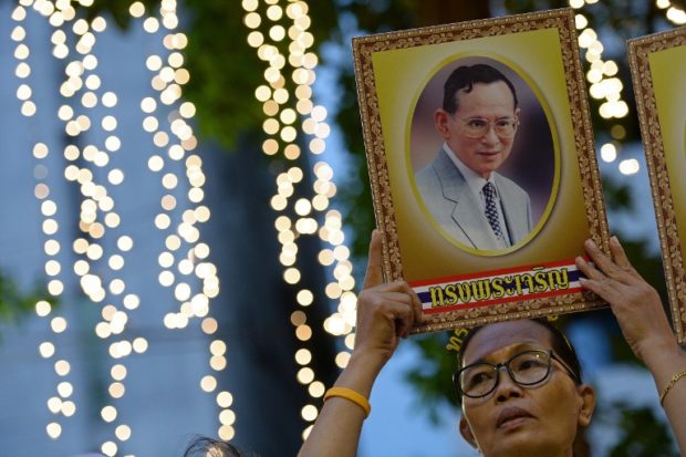 A Thai well-wisher holds a portrait of King Bhumibol Adulyadej as people gather to celebrate his 88th birthday at the Siriraj hospital where the King has been staying for months in Bangkok on December 5, 2015. Thai King Bhumibol, the world's longest reigning monarch who is regarded as a demi-god by many Thais and considered a unifying force in a politically turbulent nation, turned 88 on December 5, 2015. AFP FILE PHOTO