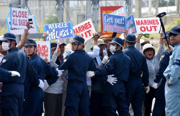Policemen (in blue) try to remove people protesting against the presence of US bases, in front of the gate of the US Marine Corps' Camp Schwab in Nago on the southern island of Okinawa prefecture on June 17, 2016. Okinawans are planning a major rally on June 19 in protest over the heavy US military presence and crimes by US personnel. / AFP PHOTO / TORU YAMANAKA