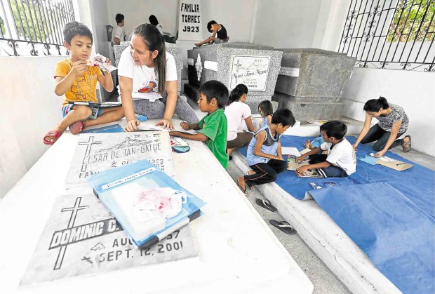 CALL IT a “home-schooling” of sorts. Children living at the Manila North Cemetery attend summer classes courtesy of All Together in Dignity, a nongovernment organization which has been conducting Ang Galing literacy classes for kids. Graves serve as both tables and chairs for the children who are taught to read and write. No complaints so far from the relatives of the departed who approve of the program while teachers and students make sure to clean up after themselves.    PHOTOS BY Lyn Rillon 