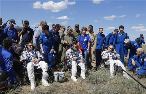 The International Space Station crew, from left, Britain's Tim Peake, Russia's Yuri Malenchenko and Tim Kopra of US, surrounded by ground personnel, rest shortly after landing near the town of Dzhezkazgan, Kazakhstan, Saturday, June 18, 2016. A three-person crew from the International Space Station has landed safely in the sun-drenched steppes of Kazakhstan. (Shamil Zhumatov/Pool Photo via AP)