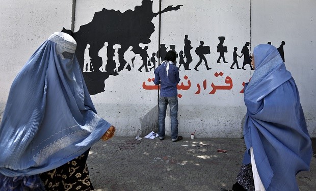 In this Wednesday, May 25, 2016 photo, Women walk past an independent Afghan artist painting graffiti on a wall with Persian that reads, "There is no peace in escaping," built to cordon off the Ministry of Communications in Kabul, Afghanistan. With every terrorist attack in Kabul, a little more of what made Afghanistan's capital a garden city of the 1960s disappears behind massive concrete walls designed to thwart suicide bombers and keep the people and buildings behind them safe. AP 