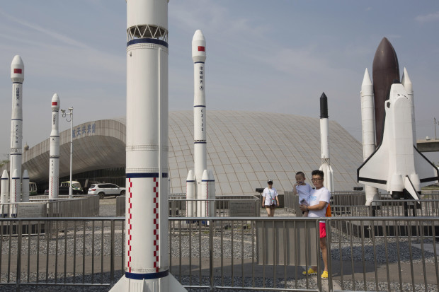 A man holds a child as they visit a park with replicas of foreign and domestic space vehicles displayed in Beijing, China, Sunday, June 26, 2016. China on Sunday recovered an experimental probe launched aboard a new generation rocket, marking another milestone in its increasingly ambitious space program that envisions a mission to Mars by the end of the decade. (AP Photo/Ng Han Guan)