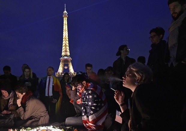 People mourn around candles at the Place Trocadero in front of the Eiffel Tower in Paris, France, to honor victims of Sunday's mass shooting at an Orlando gay club, Monday, June 13, 2016. People brought banners, flags and candles to the Place Trocadero in front of the Paris landmark. (AP Photo/Martin Meissner)