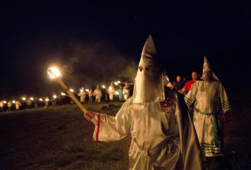 In this Saturday, April 23, 2016 photo, members of the Ku Klux Klan participate in cross burnings after a "white pride" rally in rural Paulding County near Cedar Town, Ga. Born in the ashes of the smoldering South after the Civil War, the KKK died and was reborn before losing the fight against civil rights in the 1960s. Membership dwindled, a unified group fractured, and one-time members went to prison for a string of murderous attacks against blacks. Many assumed the group was dead, a white-robed ghost of hate and violence. (AP Photo/John Bazemore)