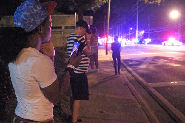 Jermaine Towns, left, and Brandon Shuford, second from left, wait down the street from the scene of a shooting involving multiple fatalities at a nightclub in Orlando, Fla., Sunday, June 12, 2016. Towns said his brother was hiding in a bathroom at the time. (AP Photo/Phelan M. Ebenhack)