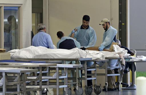 Medical personnel examine a body at the Orlando Medical Examiner's Office , Sunday, June 12, 2016, in Orlando, Fla. A gunman opened fire inside a crowded gay nightclub early Sunday, before dying in a gunfight with SWAT officers, police said. (AP Photo/Alan Diaz)