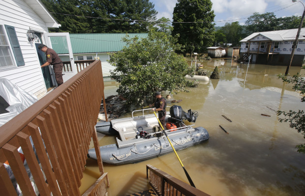 West Virginia Natural Resources police officer Chris Lester, left, walks into the top floor of a flooded home as he and Lt. Dennis Feazell search homes in Rainelle, W. Va., Saturday, June 25, 2016.  About 32,000 West Virginia homes and businesses remain without power Saturday after severe flooding hit the state. The West Virginia Division of Homeland Security and Emergency Management also said Saturday that more than 60 secondary roads in the state were closed. (AP Photo/Steve Helber)