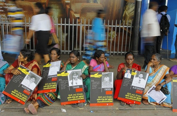 In this April 6, 2015, file photo, Sri Lankan ethnic Tamil women sit holding placards with portraits of their missing relatives as they protest out side a railway station in Colombo, Sri Lanka. For the hundreds of thousands of minority ethnic Tamils, the Sri Lankan government's repeated promises of post-war reconciliation ring false, even as authorities take tentative steps toward fulfilling some of them. Many expected a new era of healing and atonement when President Maithripala Sirisena took office in 2015, but progress has been slow as he cautiously balances the Tamils' anguished demands with the persistent fears of the Sinhalese majority.  AP FILE PHOTO