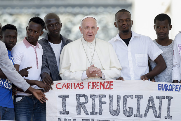 Pope Francis poses for a photo with a group of refugees he invited to join him on the steps of St. Peter's Basilica during his weekly general audience in St. Peter's Square at the Vatican, Wednesday, June 22, 2016.  Pope Francis has invited a dozen refugees to join him on the steps of St. Peter's Basilica for his general audience to press his demand for Europe to welcome more migrants. The banner reads "The refugees for a future together" (AP Photo/Fabio Frustaci)