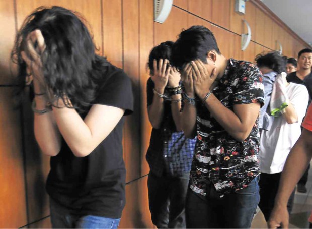  The arrested drug suspects cover their faces at the NBI media briefing on Wednesday. The bureau alleged that they operated a drug laboratory in Parañaque City, as shown by the alleged samples seized from the group. PHOTO/EDWIN BACASMAS