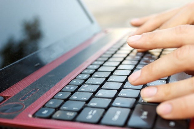 Closeup of hands on laptop keyboard. STORY: Fact-checkers call preelection fake news a ‘firehose of falsehoods’