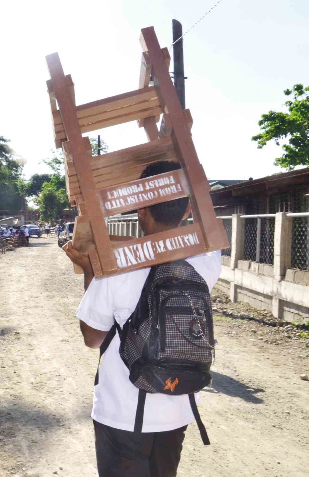 A STUDENT carries an armchair, made of illegal logs, on the first day of school at San Juan Senior High School in Batangas. GAUDENCIO DELA CRUZ/CONTRIBUTOR
