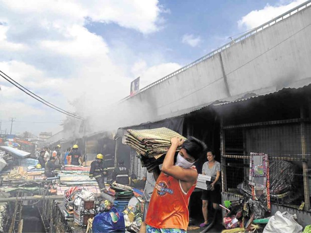 VENDORS save their goods from the burning interior of the public market in Barangay Tanyong Malabon City, on Saturday. Ritzchelle Belenzo