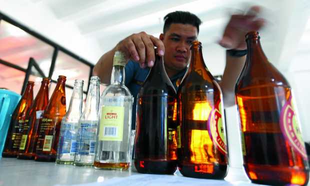 A police officer conducts an inventory of different kinds of liquors they confiscated as evidence at PNP Masambong station 2 in Quezon city during raid last night for violation of city ordinance 2301.EDWIN BACASMAS