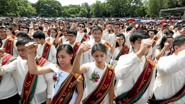 GRADUATES With the customary raising of fists as a final act during the 105th commencement exercises of the University of the Philippines, graduates of the country’s premier academic institution sing  “UP Naming Mahal” at the University Amphitheater on the UP Diliman campus in Quezon City. NIÑO JESUS ORBETA