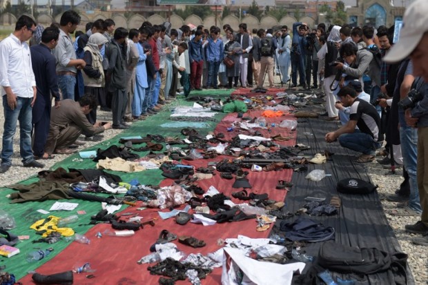 Relatives and friends inspect shoes and other belongings of those who were killed in the twin suicide attack, gathered on the ground at a mosque in Kabul on July 24, 2016 Islamic State jihadists claimed responsibility for twin explosions on July 23 that ripped through crowds of Shiite Hazaras in Kabul, killing at least 80 people and wounding 231 others in the deadliest attack in the Afghan capital since 2001. / AFP PHOTO / SHAH MARAI