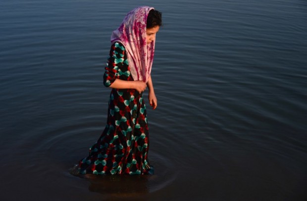 In this photograph taken on July 28, 2016, an Afghan girl stands in the Hari Rud river on the outskirts of Herat. / AFP PHOTO / AREF KARIMI