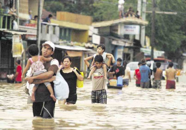 RESIDENTS of Calumpit town in Bulacan province wade through a flooded street after rains dumped by Typhoon “Pedring” in 2011 submerged a wide section of Central Luzon region. FILE PHOTO