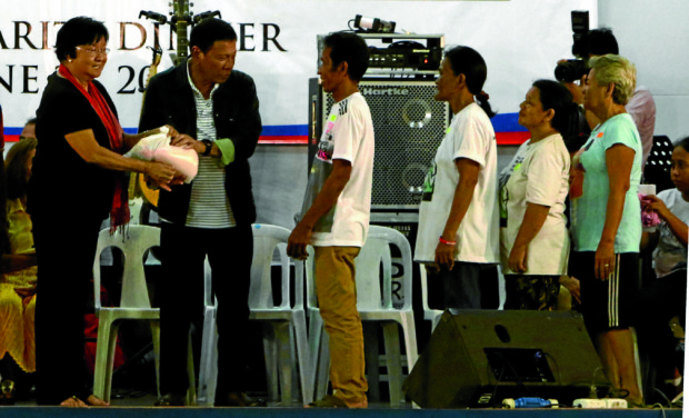 FIRST NIGHT IN POWER President Duterte and Social Welfare Secretary Judy Taguiwalo (left) hand out rice packs to Tondo residents late Thursday. RICHARD A. REYES