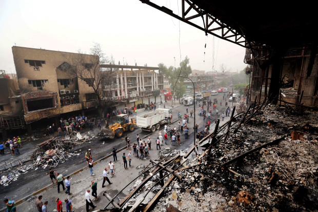 FILE -- In this Sunday July 3, 2016, file photo, Iraqi security forces and civilians gather at the site after a truck bomb hit Karada, a busy shopping district in the center of Baghdad, Iraq. As millions of Muslims around the world celebrate the end of Ramadan, many are struggling to come to grips with what has been a particularly bloody month of attacks that killed more than 350 people and spread terror across continents. (AP Photo/Hadi Mizban, File)