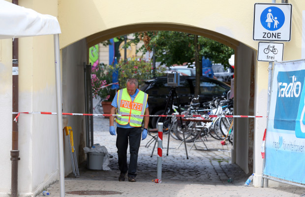 A member of the German police stands behind a police tape in Ansbach, Germany, Monday, July 25, 2016, near the site where a failed asylum-seeker from Syria blew himself up and wounded 15 people after being turned away from an open-air music festival in southern Germany. The man recorded a cell phone video of himself pledging allegiance to the Islamic State group before he tried to get into the outdoor concert with a bomb-laden backpack. (Karl-Josef Hildenbrand/dpa via AP)
