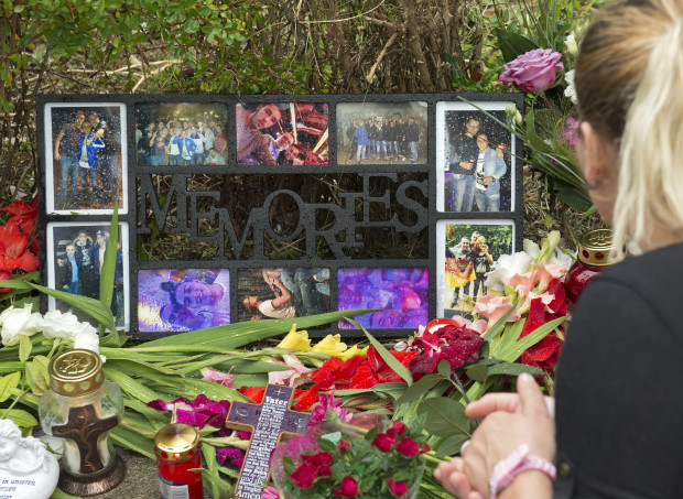 A woman mourns in front of flowers near the Olympia shopping center where a shooting took place leaving nine people dead the day before in Munich, Germany, Saturday, July 23, 2016. Police piecing together a profile of the gunman whose rampage at a Munich mall Friday left nine people dead described him Saturday as a lone, depression-plagued teenager. (AP Photo/Jens Meyer)