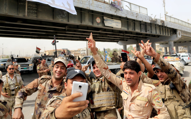 Iraqi security forces pose for pictures as they celebrate their victory in Fallujah, Iraq, Tuesday, June 28, 2016. Iraqi forces declared Sunday they had “fully liberated” Fallujah from the Sunni-led extremist group that took over the city 40 miles (65 kilometers) west of Baghdad more than two years ago. The operation, backed by airstrikes from a U.S.-led coalition, began May 22, and involved a number of different Iraqi security forces: elite special operations troops, federal police, Anbar provincial police, and an umbrella group of government-approved mostly Shiite militias. (AP Photo/Karim Kadim)