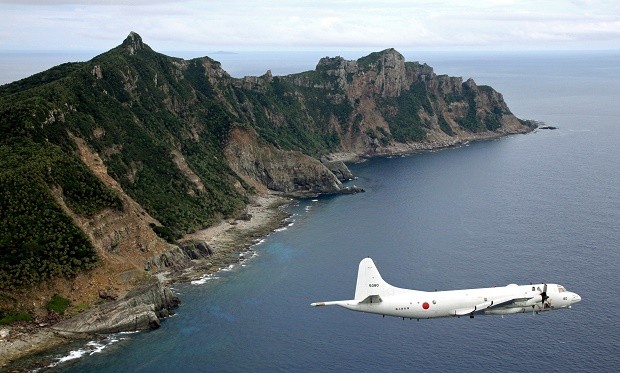 In this Oct. 13, 2011 file photo, Japan Maritime Self-Defense Force P-3C Orion surveillance plane flies over the disputed islands, called the Senkaku in Japan and Diaoyu in China, in the East China Sea.  Japan protested to China on Thursday, June 9, 2016,  after spotting a Chinese warship for the first time near disputed islands in the East China Sea.  Japanese officials said a Chinese navy frigate was seen off the coast of the Japanese-controlled Senkaku islands, also claimed by China and called the Diaoyu islands. The ship did not violate Japan's territorial waters, and it has since left the area. Kyodo News via AP, File