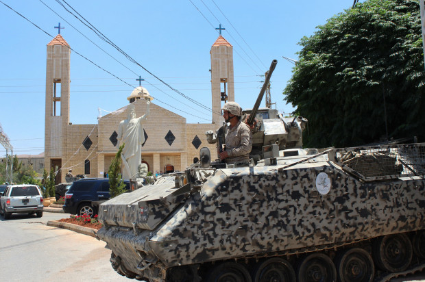 A Lebanese army soldier from the special forces unit stands on a APC during a patrol in front a church in Qaa, a predominantly Lebanese Christian village near the Syrian border were suicide bombers blow themselves among civilians on Monday, eastern Lebanon, Tuesday, June 28, 2016. Lebanese troops detained 103 Syrians for illegal entry into the country, in a security sweep on Tuesday, a day after a series of deadly bombings struck a village near the border with Syria, the military said. The unprecedented attacks nine explosions in all, eight of them suicide bombings triggered fear and panic among residents of Qaa village and a deepening sense of foreboding in Lebanon, which has grappled for over five years with spillovers from neighboring Syria's civil war. (AP Photo)