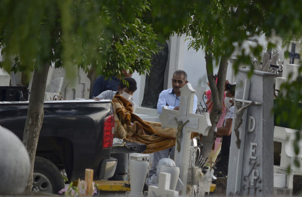 Forensic and cemetery workers unload the bodies of 11 slain family members from a police pick-up truck at a cemetery in the city of Tehuacan, Mexico, Friday, June 10, 2016. Five women, four men and two girls from the same family were found shot to death on Thursday in the town of San Jose el Mirador in Puebla's state municipality of Coxcatlan, in central Mexico. The prime suspect in the brutal slaying is a man who allegedly sought revenge after one of the victims reported that he raped her and he was jailed, a Mexican law enforcement official said Saturday. (AP Photo/Pablo Spencer)