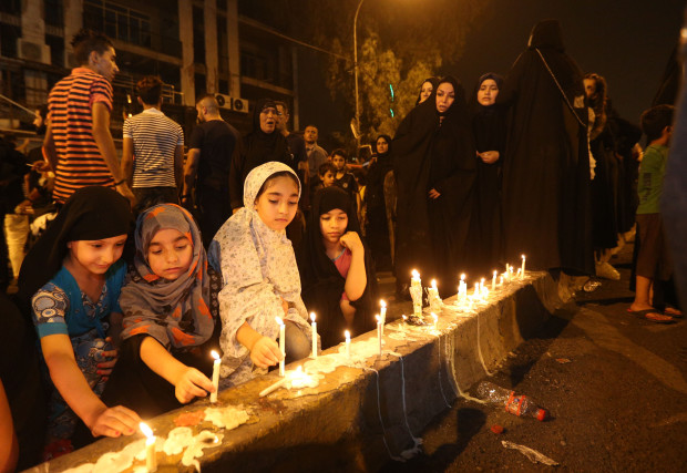 People light candles at the scene of a massive car bomb attack in Karada, a busy shopping district where people were shopping for the upcoming Eid al-Fitr holiday, in the center of Baghdad, Iraq, Monday, July 4, 2016. (AP Photo/Hadi Mizban)