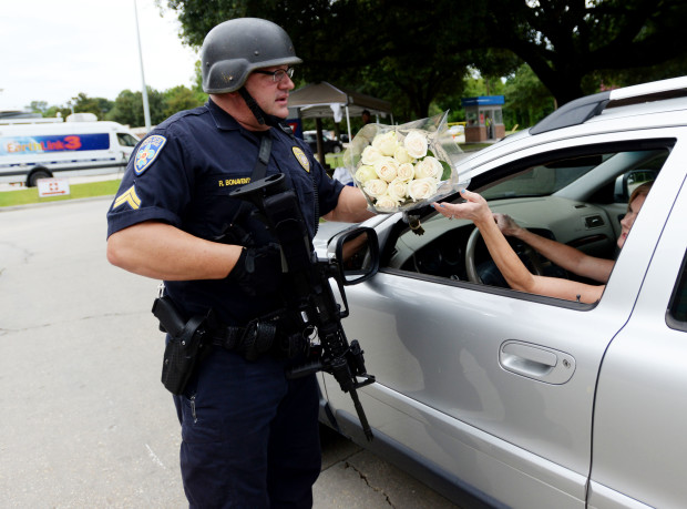 Baton Rouge police officer Randy Bonaventure takes a bouquet of flowers at the Our Lady of the Lake Hospital where the police officers were brought this morning, Sunday, July 17, 2016. Multiple law enforcement officers were killed and wounded Sunday morning in a shooting near a gas station in Baton Rouge. (Henrietta Wildsmith/The Times via AP)