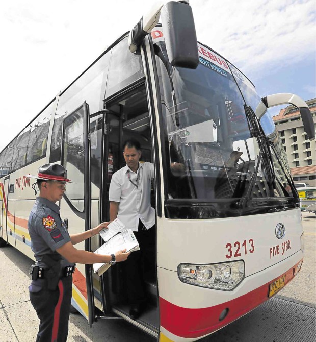 A MEMBER of the PNP-Highway Patrol Group inspects the papers  of a passenger bus on Edsa, Pasay, during Thursday’s joint anticolorum operation with the MMDA, LTFRB and LTO. RAFFY LERMA