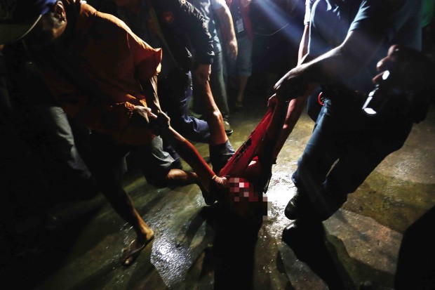 MASSACRE AMONG THE TOMBS  Policemen and residents carry the body of one of the five people shot dead by unidentified gunmen inside a public cemetery in Malabon City late Tuesday night. RAFFY LERMA