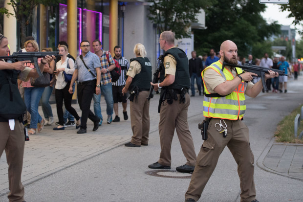 Police escort people who leave the Olympia mall in Munich, southern Germany, Friday, July 22, 2016 after shots were fired. Police said that at least six people have been killed. (AP Photo/Sebastian Widmann)