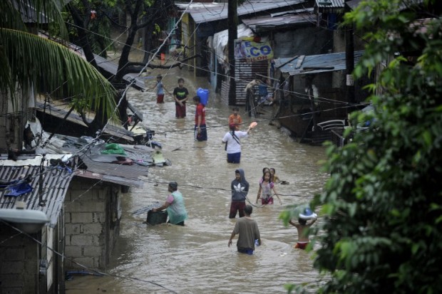 Residents wade through a flooded street in San Mateo, Rizal province, east of Manila on August 13, 2016. Floods inundated major thoroughfares in the capital late on August 12, after heavy rains brought about by southwest moonson, authorities said on August 13. / AFP PHOTO / NOEL CELIS