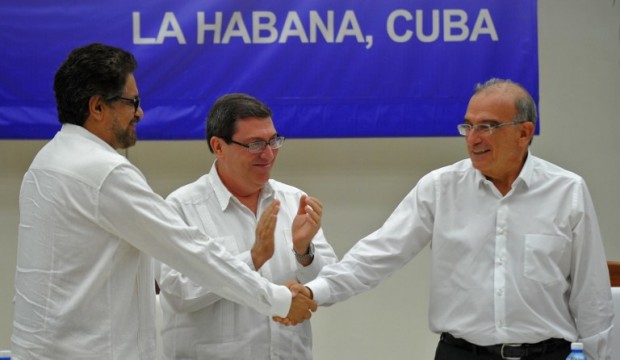 Colombian government head of delegation for peace talks Humberto de la Calle (R) and FARC-EP Commander Ivan Marquez (L) shake hands upon the signing of the agreement at the conclusion of the peace talks in Havana at the Convention Palace in Havana, on August 24, 2016. At center Cuban Foreign Minister Bruno Rodriguez. Colombia's government and FARC rebels announced Wednesday that they have reached a historic peace accord to end their half-century civil war, the last major armed conflict in the Americas. / AFP PHOTO / YAMIL LAGE