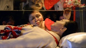 Former first lady Imelda Marcos kisses the glass case that contains the frozen remains of former dictator and president Ferdinand Marcos on July 2, 2014. (AFP FILE PHOTO/TED ALJIBE)
