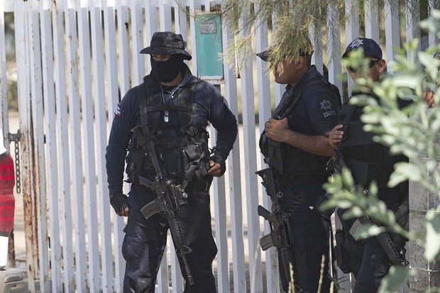  In this May 22, 2015, file photo, Mexican state police stand guard near the entrance of Rancho del Sol, where a shootout with the authorities and suspected criminals happened near Vista Hermosa, Mexico. Mexico's National Human Rights Commission said on Thursday, Aug. 18, 2016, that it has concluded that 22 people were arbitrarily executed by federal police during the event. Commission President Luis Raul Gonzalez Perez said their investigation revealed a range of human rights abuses on the part of government forces. AP FILE PHOTO