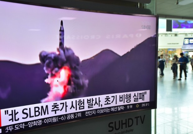 People walk past a television screen at a railway station in Seoul on July 9, 2016, showing file footage of a North Korean missile launch. North Korea on July 9 test-fired what appeared to be a submarine-launched ballistic missile (SLBM), Seoul's defence ministry said, a day after the US and South Korea decided to deploy an advanced missile defence system in the South. / AFP PHOTO / JUNG YEON-JE