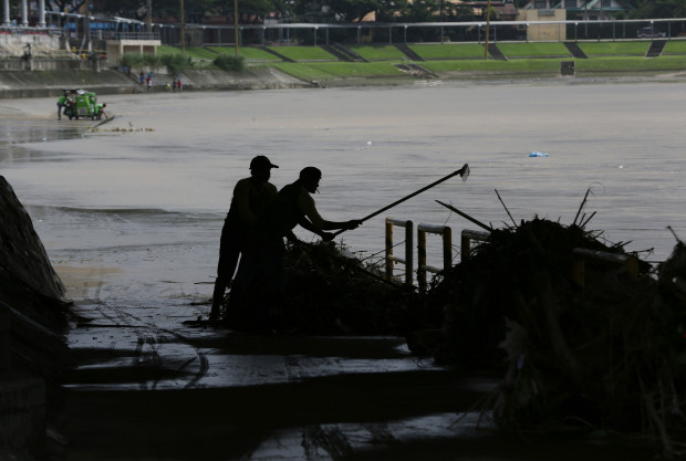 Filipino workers clean up debris washed along the banks of a swollen river in Marikina, east of Manila, Philippines Monday, Aug. 15, 2016. Thousands of residents living along a swollen river were forced to evacuate on Sunday following heavy southwest monsoon rains that inundated low-lying areas in Metropolitan Manila and at least four provinces in the country's Luzon island. (AP Photo/Aaron Favila)