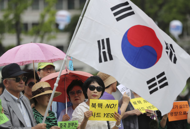 South Koreans hold signs and a national flag during a rally to support a plan to deploy an advanced U.S. missile defense system called Terminal High-Altitude Area Defense, or THAAD, in Seoul, South Korea, Monday, July 18, 2016.  The advanced U.S. missile defense system will be deployed in a rural farming town in southeastern South Korea, Seoul officials announced Wednesday, July 13, angering not only North Korea and China but also local residents who fear potential health hazards that they believe the U.S. system might cause. The letters read "No, North Korea's Nuclear and Yes, THAAD." AP