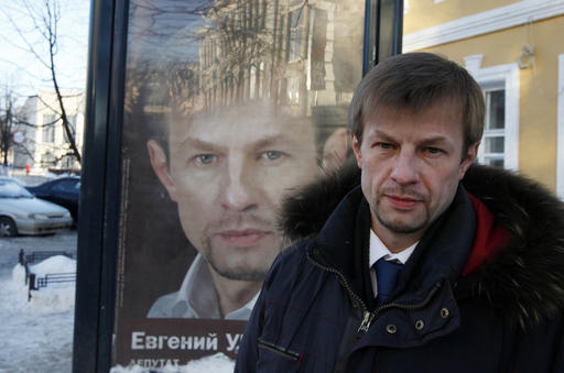 FILE - In this Jan. 24, 2012 file photo Yevgeny Urlashov stands in front of his mayoral campaign poster in downtown Yaroslavl, city of about 590,000 some 250 kilometers (150 miles) east of Moscow, Russia. The mayor of the Russian city of Yaroslavl has been found guilty of soliciting bribes and sentenced to 12 and a half years in a high-security prison, on Wednesday, Aug. 3, 2016, an unusually harsh verdict. (AP Photo/ Sergei L. Loiko, File)