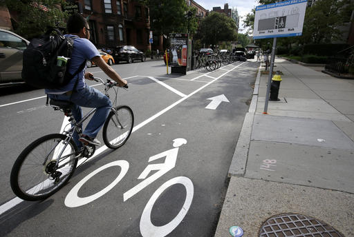 In this Tuesday, Aug. 16, 2016, photo, a cyclist enters a bike lane that is routed between parked cars and the sidewalk in Boston. Cities around the world are increasingly changing bike lanes to make them safer in light of fatal crashes involving cyclists and cars. (AP Photo/Steven Senne)