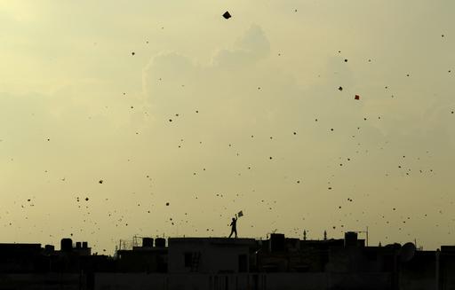 In this Aug. 15, 2013 file photo, a boy flies a kite from the roof of a house as other kites seem to flock in the sky above as Indians celebrate Independence Day in New Delhi, India. Indian police say three people, including two children, have died after their throats were slashed by glass-coated kite string used in competitions to slice the strings of other kites.The deaths occurred in New Delhi on Monday, which was a holiday on account of India's Independence Day when people fly kites to celebrate. AP