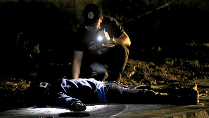 ANOTHER VICTIM Policemen inspect the body of one of twomen riding on amotorcycle who were shot and killed during an encounter with lawmen along C3 Road in Caloocan City on Sunday. Packets of “shabu” (methamphetamine hydrochloride) were reportedly found on the dead men. RAFFY LERMA