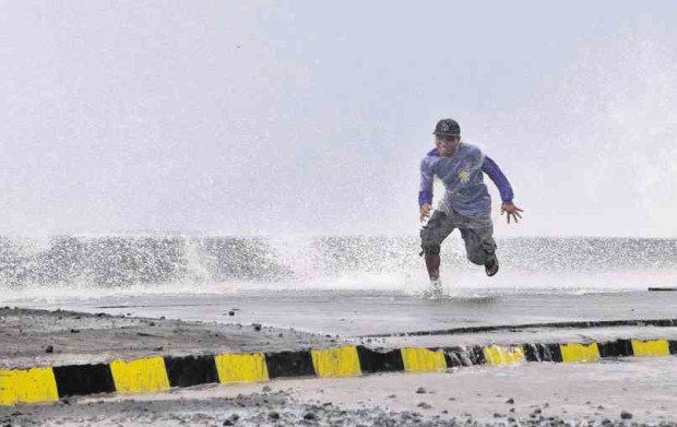 A MAN avoids being drenched as strong waves whipped up by winds accompanying Typhoon “Nona” last year hit a sea wall along Legazpi City Boulevard in Albay province. MARK ALVIC ESPLANA / Inquirer Southern Luzon